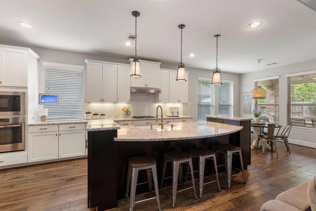 A kitchen with all the bells and whistles! The island provides additional seating and storage beneath a trio of upgraded pendant lighting.