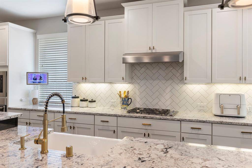 Additional highlights include a large apron sink, white shaker cabinetry and under cabinet lighting.