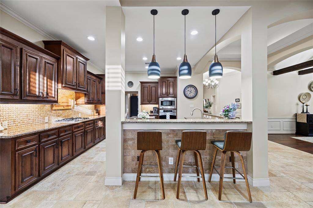 The sprawling island with breakfast bar seating serves as a versatile centerpiece, providing additional workspace, storage, and seating for casual dining or entertaining.
