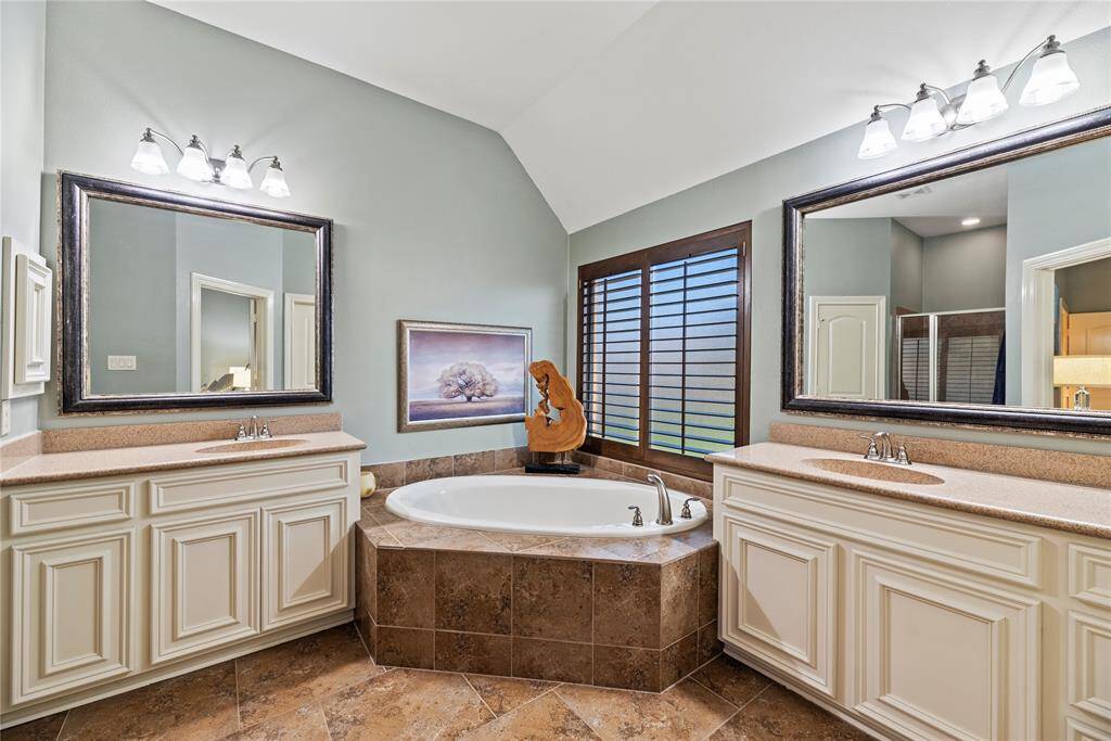 The primary bath features exquisite dual vanities, providing ample personal space along with an abundance of custom cabinetry for seamless organization.
