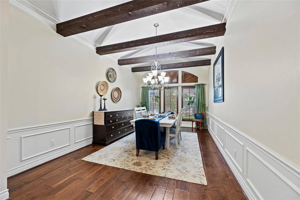 The formal dining room exudes elegance with its rich engineered wood floors, intricate crown molding, and striking exposed wood beams. This warm, inviting space is perfect for hosting everything from intimate dinners to festive gatherings, making every occasion feel special.