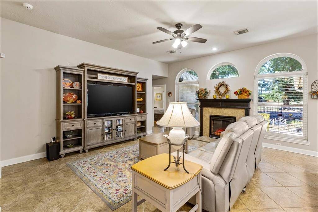 The living room features beautiful large tile flooring and offers an ideal space for a large screen TV. With its spacious layout, this room is perfect for relaxing and entertaining, providing a comfortable setting for movie nights or casual get-togethers.