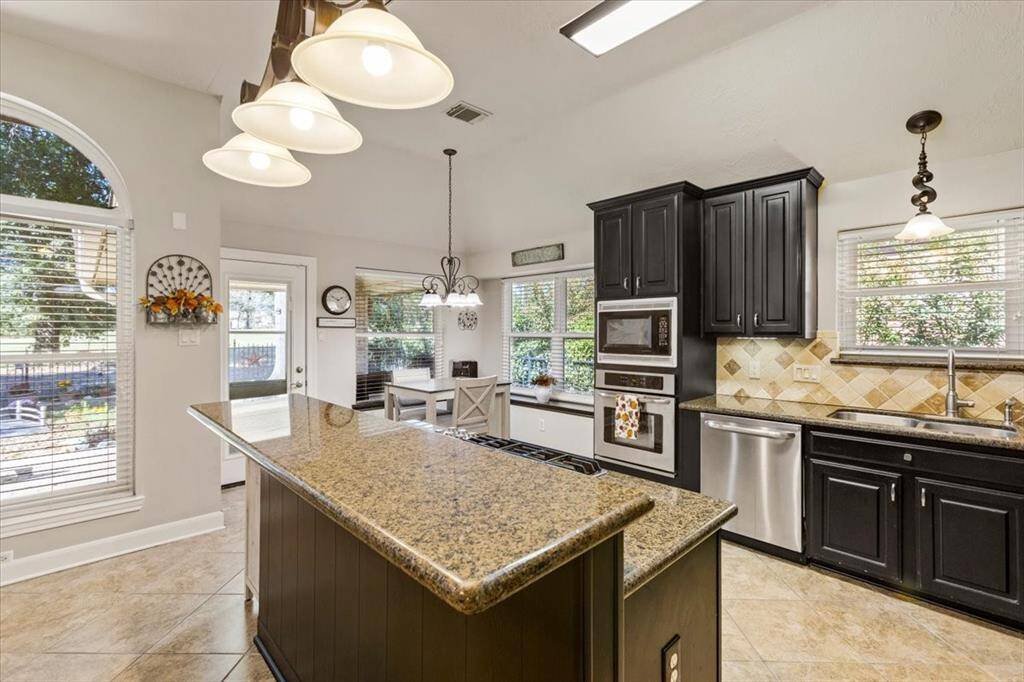 The kitchen is perfectly designed for gatherings, featuring a welcoming bar that invites friends and family to sit and enjoy each other's company. The centerpiece is a convenient island with a 5-burner range, making meal preparation a social experience while providing ample space for cooking and entertaining.