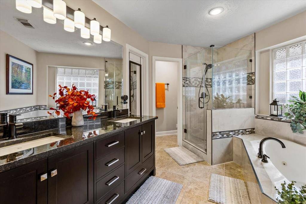 This alternate view showcases the beautifully finished primary bathroom, highlighting its thoughtful design and high-quality materials. From the stylish cabinetry to the elegant tile work, every detail has been carefully curated to create a luxurious yet inviting space for relaxation and rejuvenation.