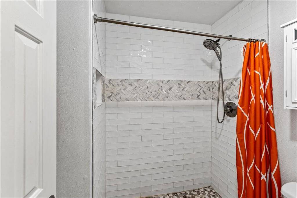 The block tiles and spacious shower enhance the feeling of openness in the secondary bathroom. These design elements not only create a contemporary aesthetic but also contribute to a more expansive atmosphere, making the bathroom feel larger and more inviting.