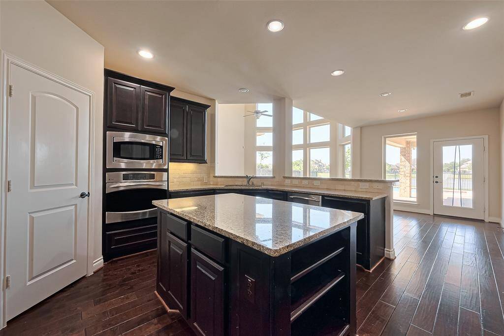 The kitchen features granite countertops, a center island, stainless steel appliances, and undermount lighting.