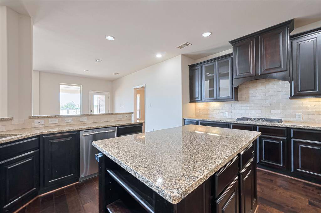The kitchen features granite countertops, a center island, stainless steel appliances, and undermount lighting.
