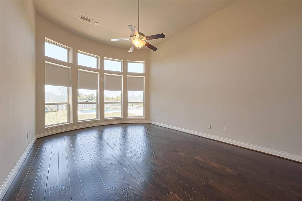 The primary bedroom features that incredible LAKE VIEW, beautiful hardwood floors, and ceiling fan.