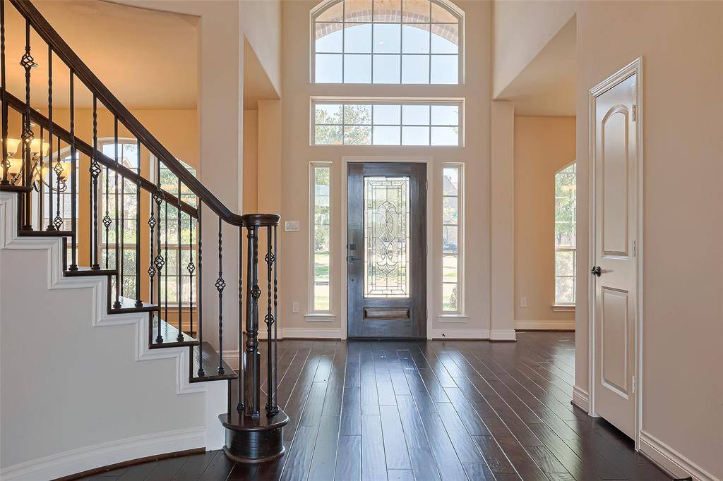 The grand entryway illuminated with so much natural light featuring the curved staircase and beautiful wood floors.  A coat closet and half bath are conveniently tucked away down the hall on the way towards the living area.