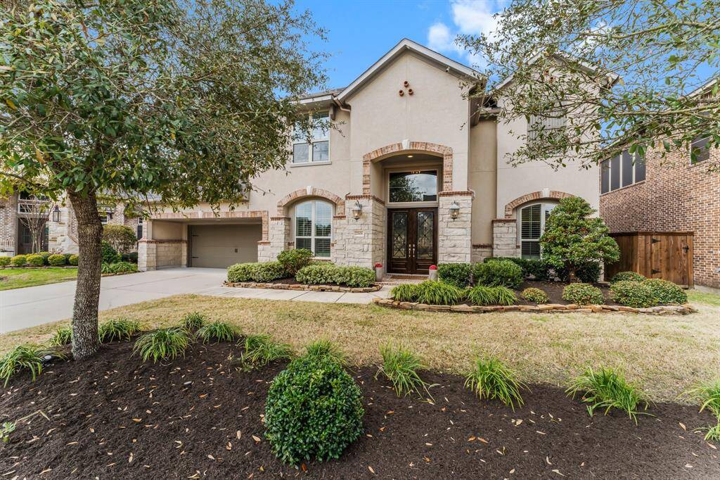 This two-story home features an inviting exterior with stone accents and a beautifully landscaped front yard.