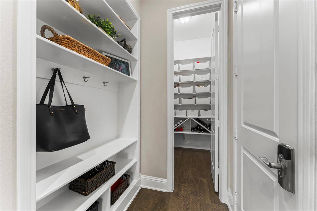 This photo showcases a well-organized pantry with built-in shelving, ample storage space, and a wine rack, featuring hardwood floors and bright lighting.