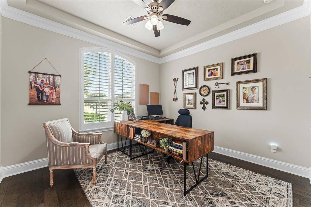 This photo shows the bright home office with a large window and elegant ceiling fan, creating a cozy and productive workspace.