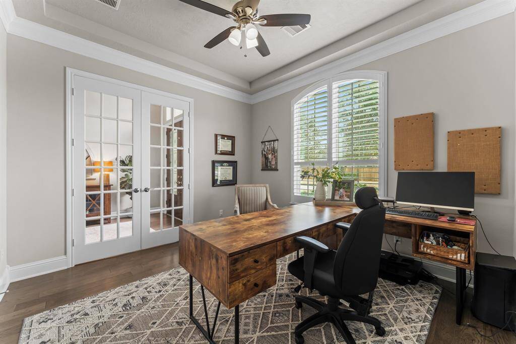 The home office features French doors, and a view of the front lawn. The room has a neutral color palette creating a cozy yet professional atmosphere.