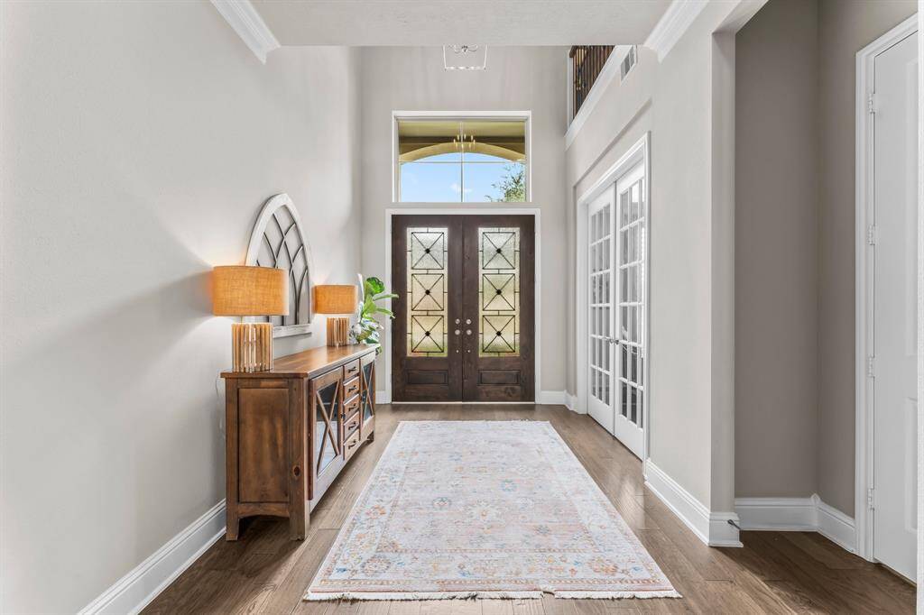 Bright and inviting foyer with high ceilings, a large window above the front doors.