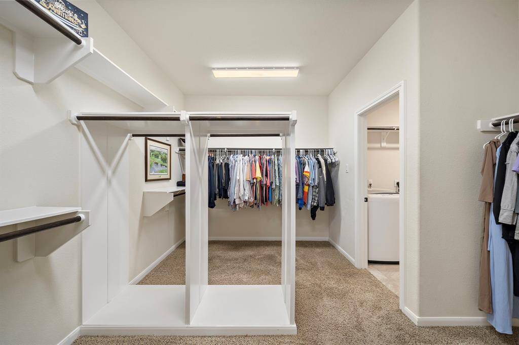 Oversized primary closet with numerous areas to hand clothes and store items.