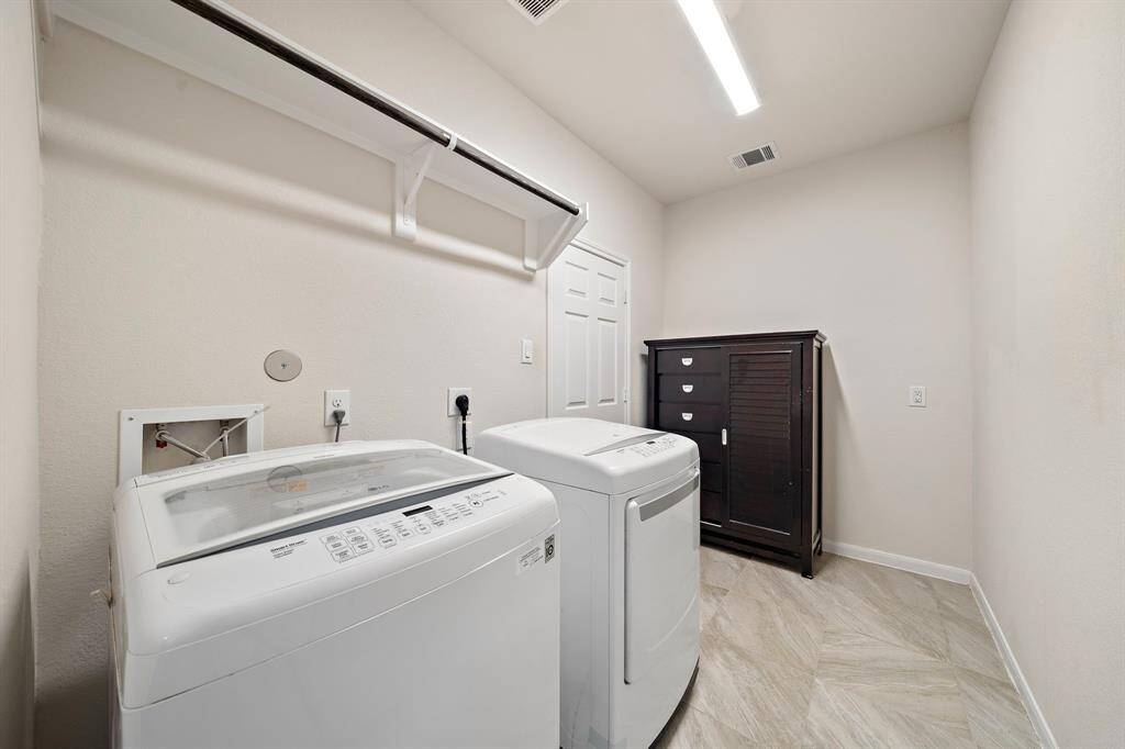 Oversized laundry room with a hanging rack and plenty of space for storage or a refrigerator.