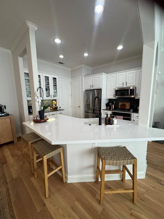 Large island with sink, breakfast bar, pantry and door to garage. Glass front cabinets loads of storage and excellent lighting.