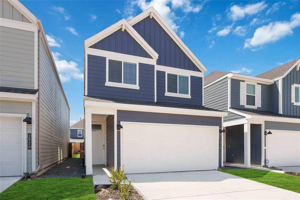 Modern two-story home with a blue and white exterior, featuring a double garage, and covered patio.