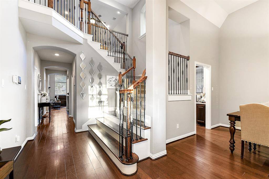 This elegant foyer offers a warm and inviting entry, setting the tone for the rest of the home. It provides easy access to the upstairs, ensuring a smooth flow throughout the space. To the right, you'll find the formal dining room, which seamlessly leads to the kitchen through a convenient built-in office nook, perfect for managing daily tasks or working from home.