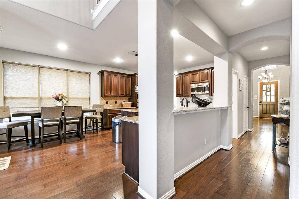 Showcasing an open floor plan, this home features consistent wood flooring throughout, seamlessly tying together the rich tones of the cabinetry and front door. The beautiful white and gray color palette enhances the home's modern yet inviting feel, creating a cohesive and elegant living space.