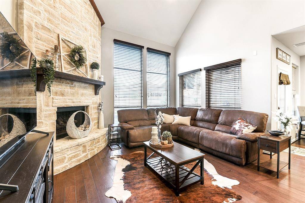 The spacious living room features a stunning floor-to-ceiling stone gas fireplace, serving as a warm and inviting focal point. To the left, you'll find the generous primary suite, while to the right, the breakfast room offers back doors that open to the outdoors—filling the space with natural light and providing easy access to the side yard for seamless indoor-outdoor living.