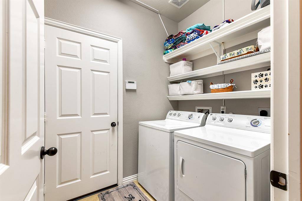 The first-floor laundry room is both functional and convenient, with a door leading directly to the 2-car garage. It features built-in shelving, offering additional storage space and organization for all your laundry essentials.