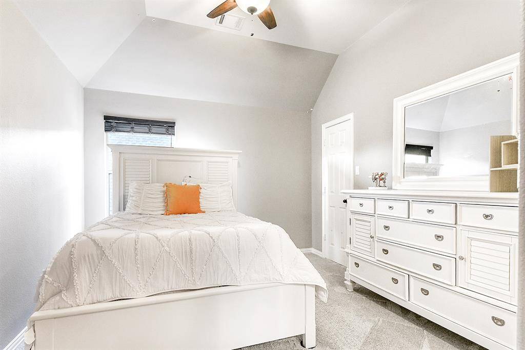 This upstairs guest bedroom features high ceilings with a drop-down fan.  It offers a sizable closet and plush carpet, creating a cozy and inviting space. The room is conveniently attached to a Hollywood-style bathroom, making it perfect for family or guests.