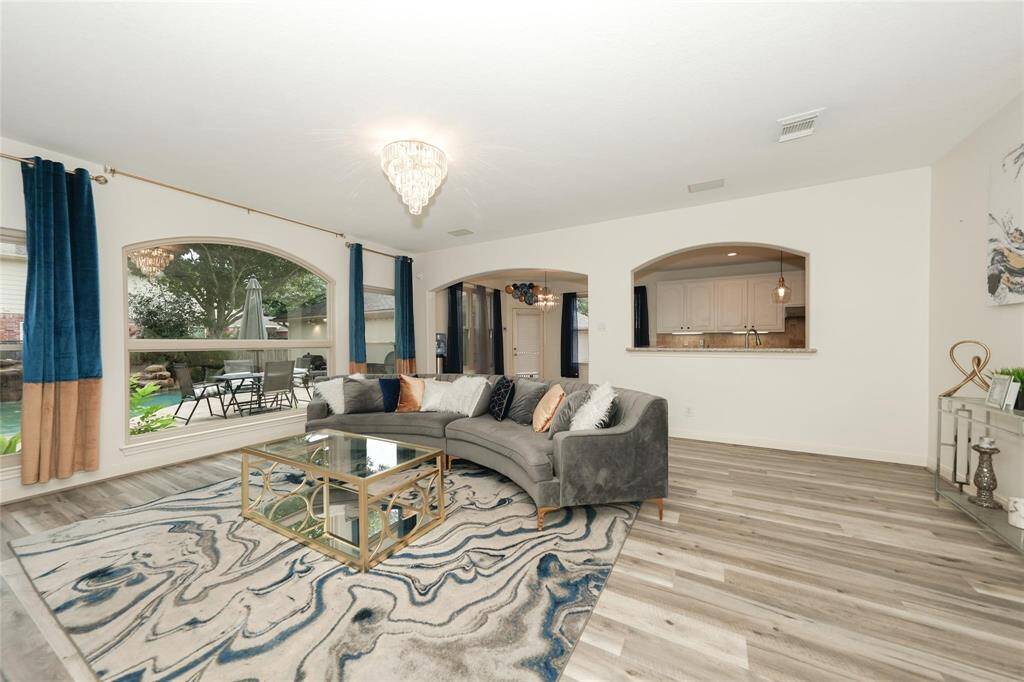 Bright living room with large windows, modern decor, and a view of the backyard. Features a cozy sectional sofa, stylish rug, and an open layout leading to the kitchen. Perfect for entertaining.