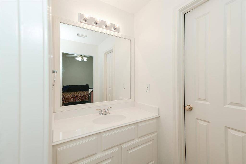 This photo shows a bright bathroom with a large mirror, a sink with a modern faucet, ample counter space, and storage cabinets below.