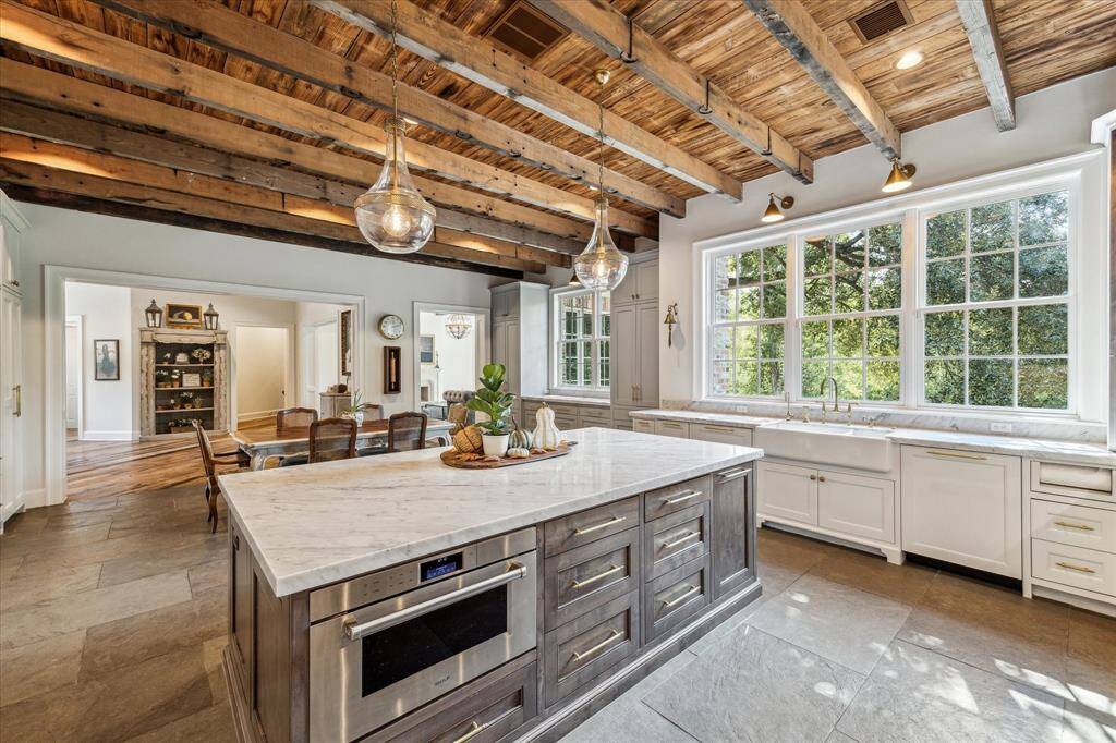 Immense island created with contrasting stained wood cabinetry & honed Carrera marble counters. Wolf steam convection oven is perfect for preparing seafood or baking cheesecake!