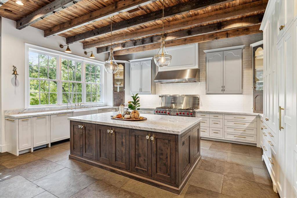 Wolf professional restaurant-grade combination gas/electric range features two 30" convection ovens, 6-burner cooktop, grill & heat lamp. Note distinctive lighted corner display cabinetry fashioned from reclaimed wood.