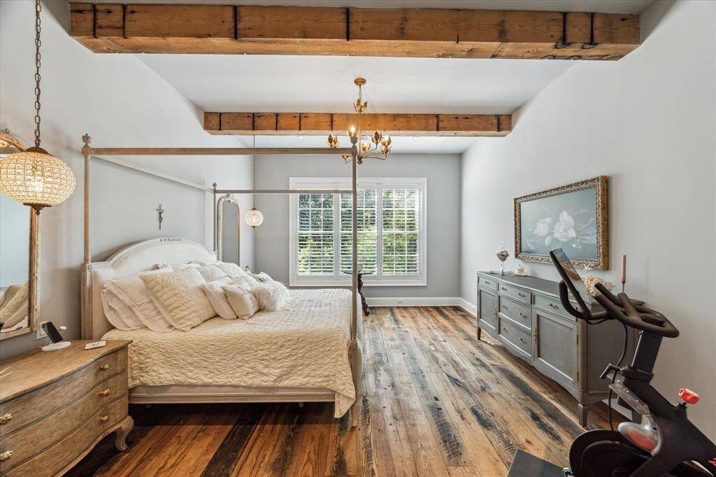 Expansive private Primary Suite boasts 11' ceilings with rustic antique wood beams & tranquil backyard views.