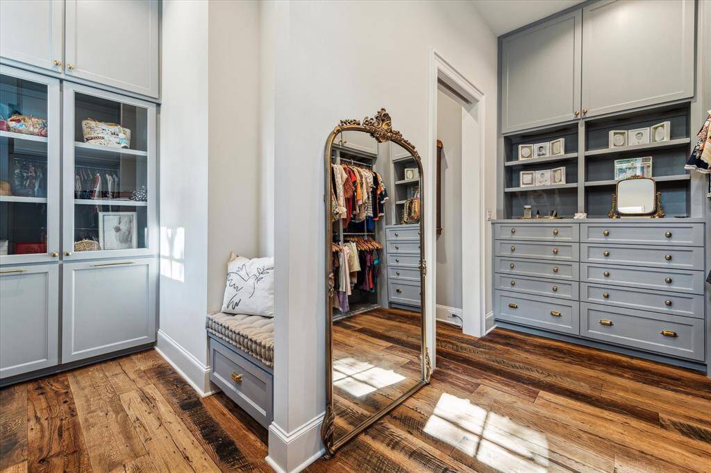 One of two massive primary closets with custom cabinetry & storage, reclaimed hardwood floors & brass hardware.