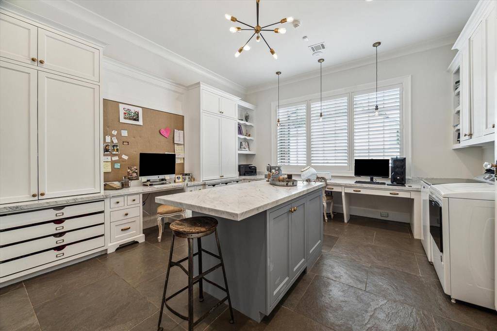 First floor Flex/Work Room is tucked away & features the perfect set up for second home office or work room: Custom cabinetry with abundant storage, island with marble counter, built-in desks, oversize limestone flooring & first floor utility room.