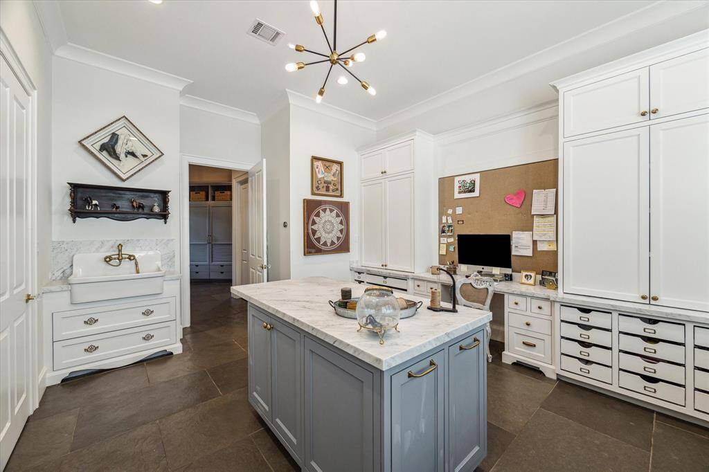 Custom built-ins & drawers, island with contrasting cabinetry, farmhouse sink & whimsical fixture create the perfect space for projects, homework or second home office!