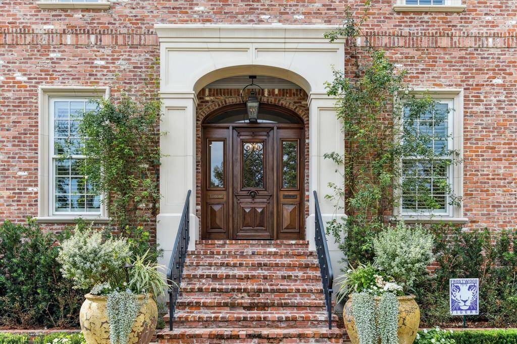 Exquisite antique door imported from France welcomes visitors to this beautifully crafted home. Brass antique mail slot is imported from Belgium, and this closer view highlights the beauty of the landscaping that graces the home.