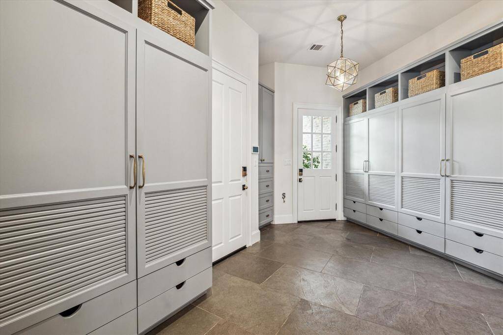 Well-appointed mud room is adjacent to first floor flex/work room & garage. Abundant custom lockers help organize household & sports gear with oversize limestone flooring that is attractive & easy to maintain.