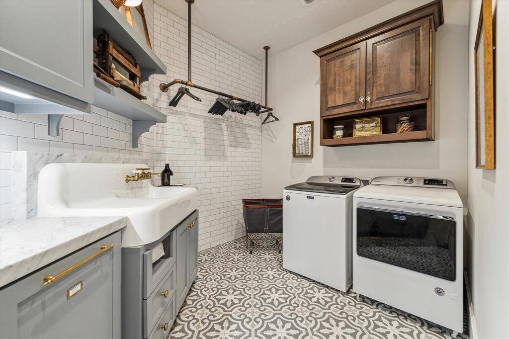 Second floor utility room is ideally situated close to secondary bedrooms. Custom cabinetry, marble counters, floor-to-ceiling tile surround, farmhouse sink with integrated drain board, handmade hanging rack & attractive tile flooring.