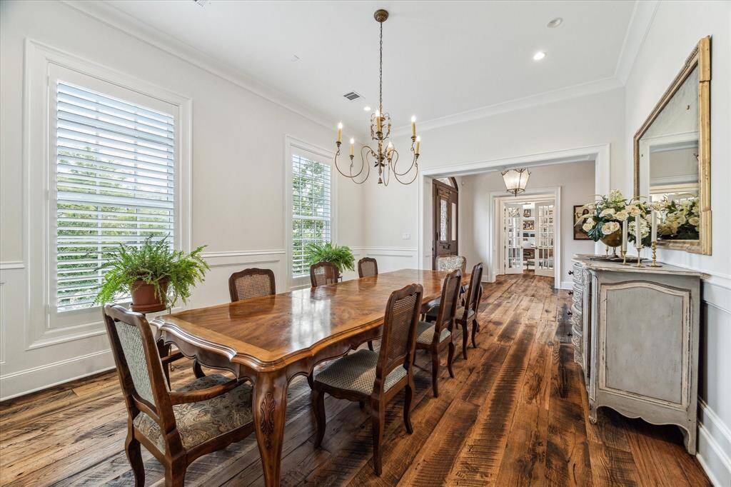 Gracious dining room boasts reclaimed hardwood floors, elegant chandelier & large dual-pane windows with timeless plantation shutters.