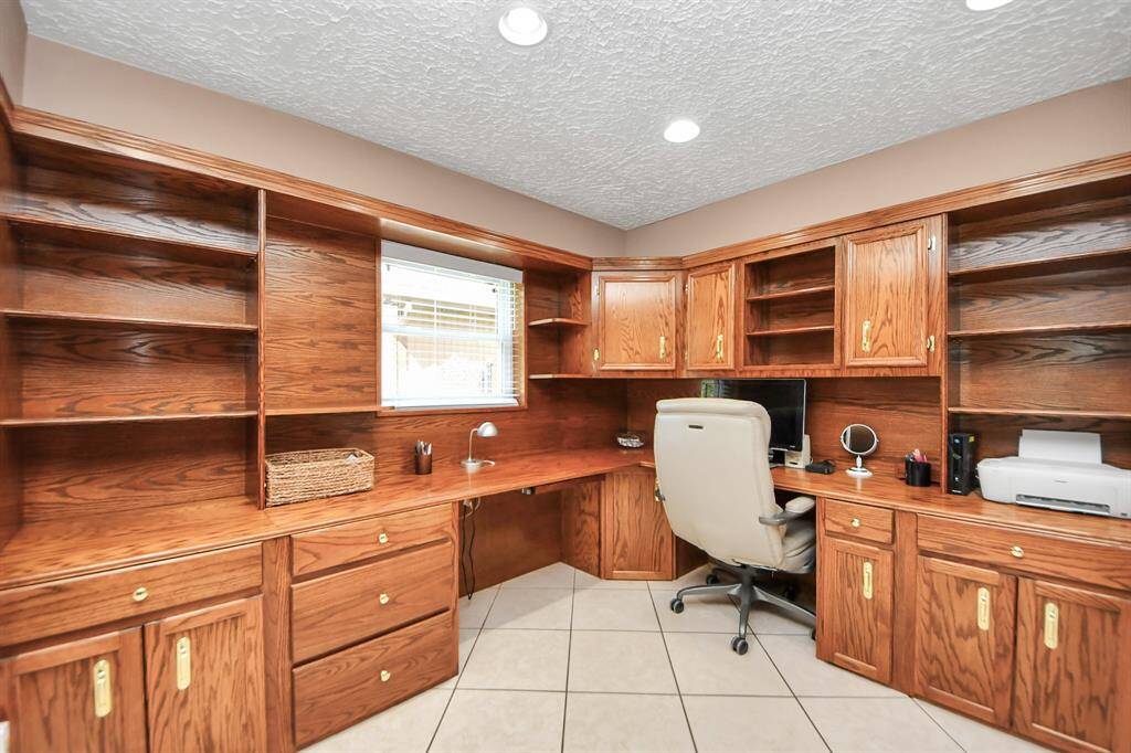 Office area with abundant wood storage cabinets and bookshelves.