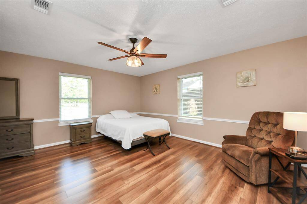 Grand Primary Suite with sitting area and laminate wood flooring overlooking the backyard paradise.