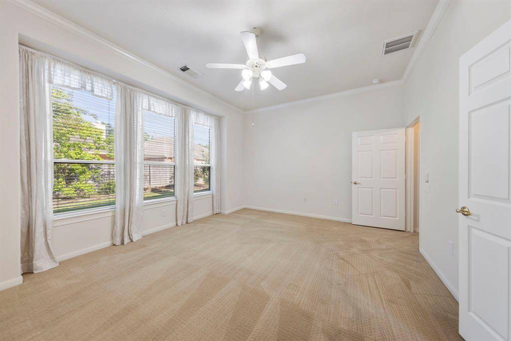 The spacious and private primary suite features a ceiling fan and an abundance of windows, creating a bright and comfortable retreat.