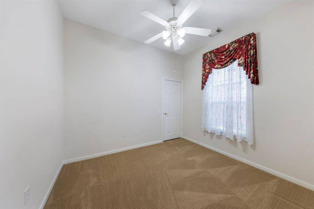 A secondary bedroom features plush carpet, a large window for natural light, and a spacious walk-in closet.