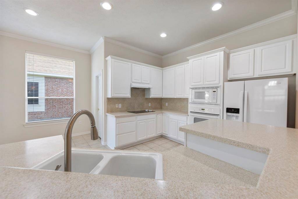Features include a spacious breakfast bar and sleek recessed lighting, perfect for casual dining and a modern touch.
