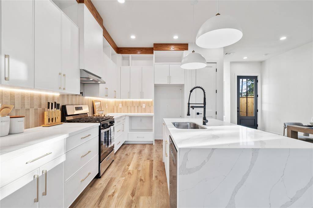 A gourmet chef’s kitchen featuring a sleek, modern design with quartz waterfall countertops on a spacious island, providing both workspace and casual seating.