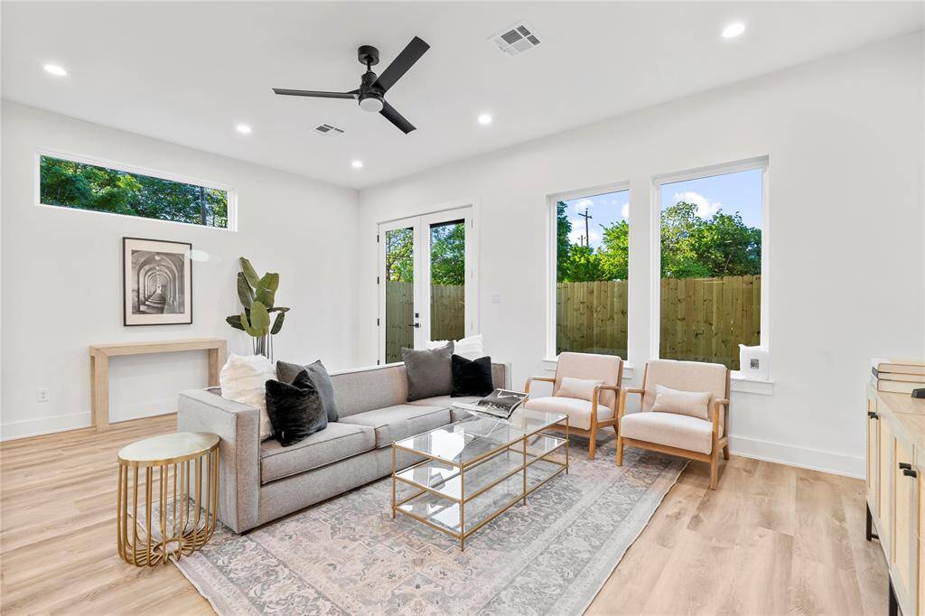 A bright, airy living room featuring high ceilings, large windows for natural light, and elegant recessed lighting.