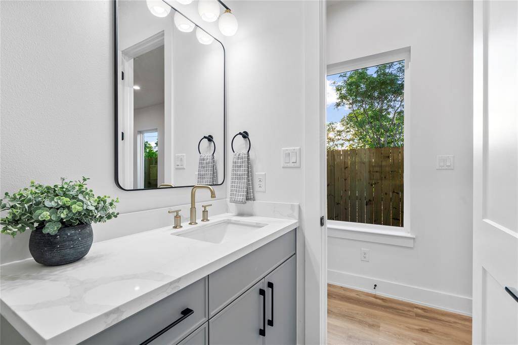 The half bathroom includes a vanity with quartz countertops, a contemporary sink, and a stylish gold faucet for a touch of elegance.