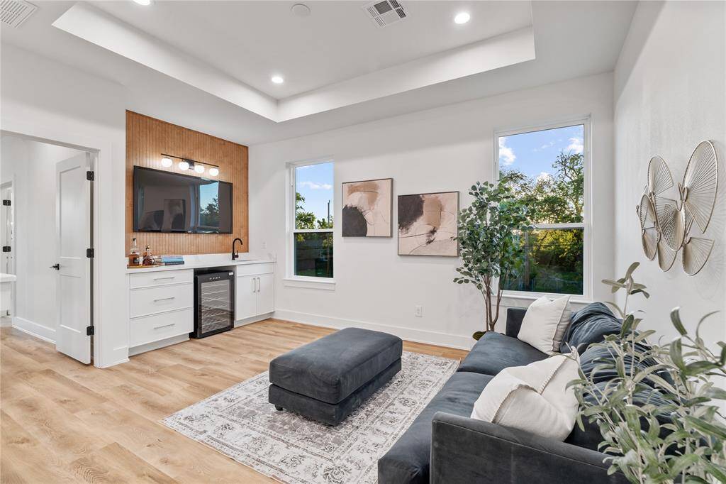 A versatile upstairs flex space designed for entertainment, complete with a built-in media center, a sleek wet bar, and a dedicated wine fridge area.