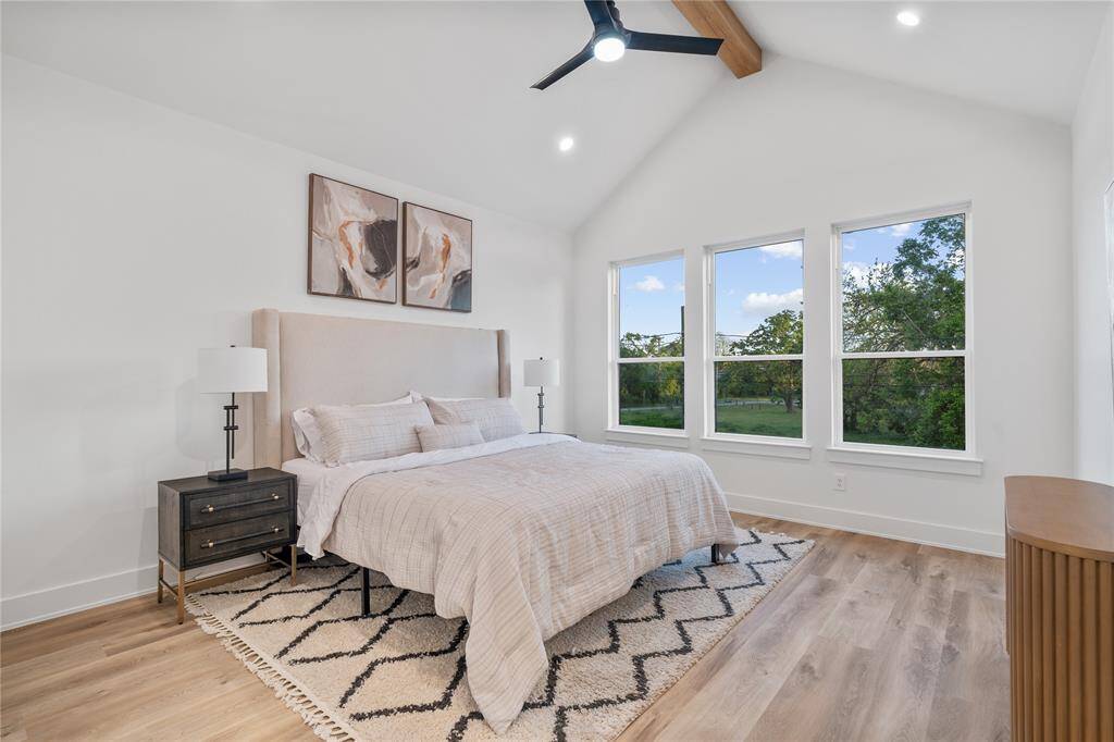A luxurious primary suite with soaring cathedral ceilings, oversized windows that bathe the room in natural light, and wide plank luxury LVP floors.