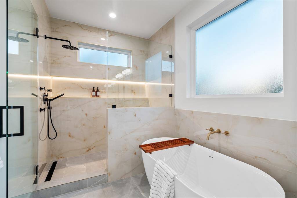 The primary bathroom is a true spa retreat, featuring a luxurious freestanding soaking tub and an expansive walk-in shower designed for both relaxation and functionality.